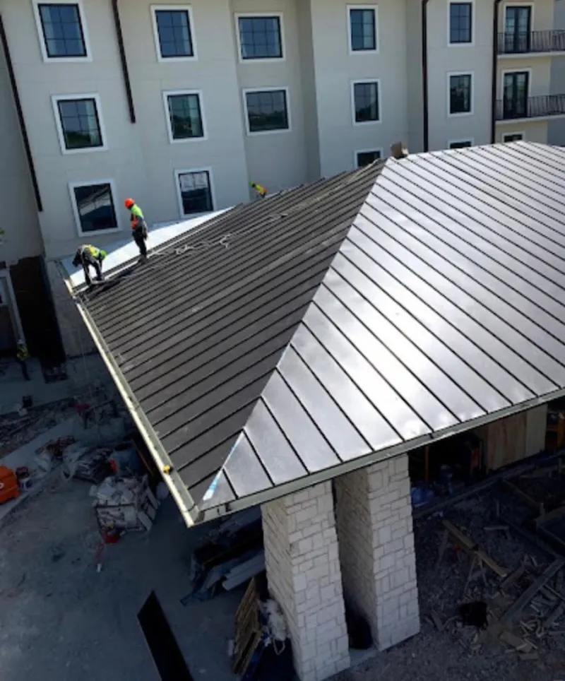 Crew installing standing seam metal roof panels on a commercial project in Orrville